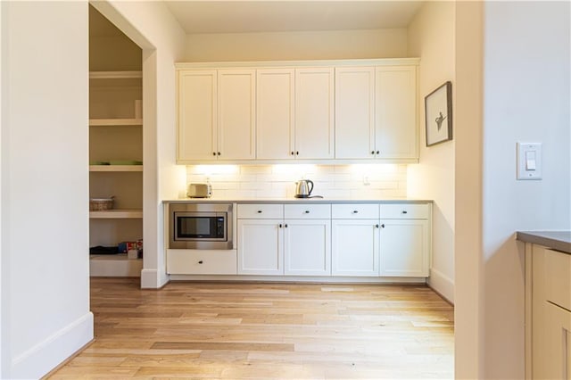 2067 Telfair Cir Unit A & B, Atlanta, GA 30324 - kitchen featuring stainless steel microwave, light wood-type flooring, white cabinets, backsplash, and baseboards