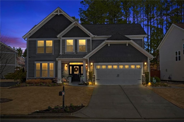 view of front of house with driveway, stone siding, and an attached garage