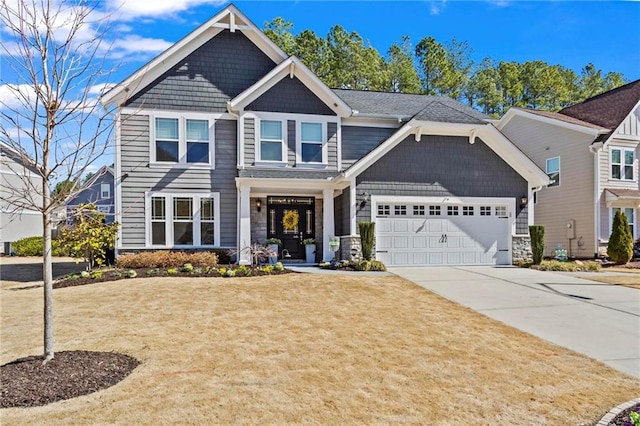 craftsman-style home with a garage, driveway, stone siding, and a front yard