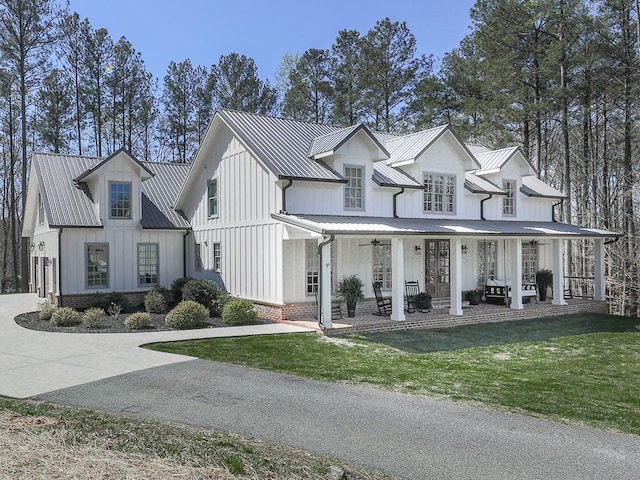 modern farmhouse style home featuring covered porch and a front lawn