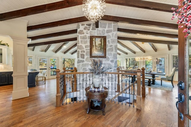 interior space with french doors, ornate columns, lofted ceiling with beams, and a notable chandelier