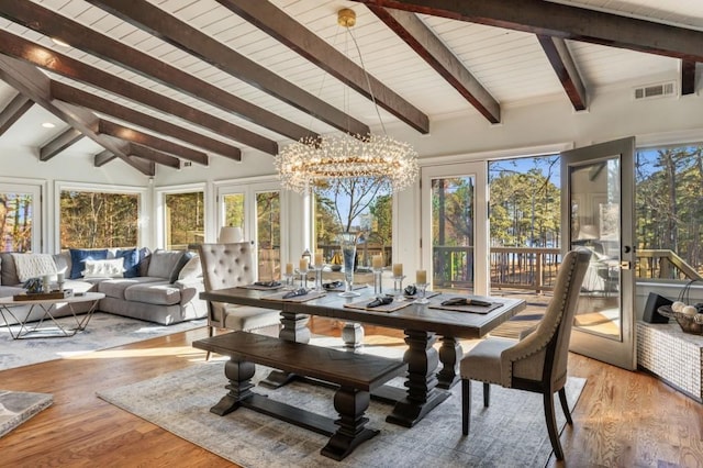 sunroom / solarium with french doors, a wealth of natural light, lofted ceiling with beams, and a notable chandelier