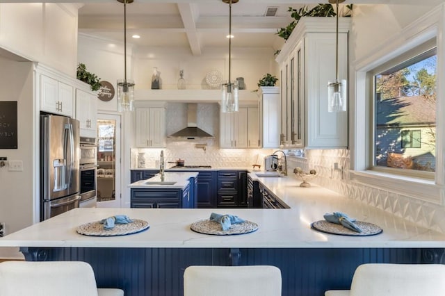 kitchen with blue cabinets, pendant lighting, wall chimney range hood, and a kitchen breakfast bar