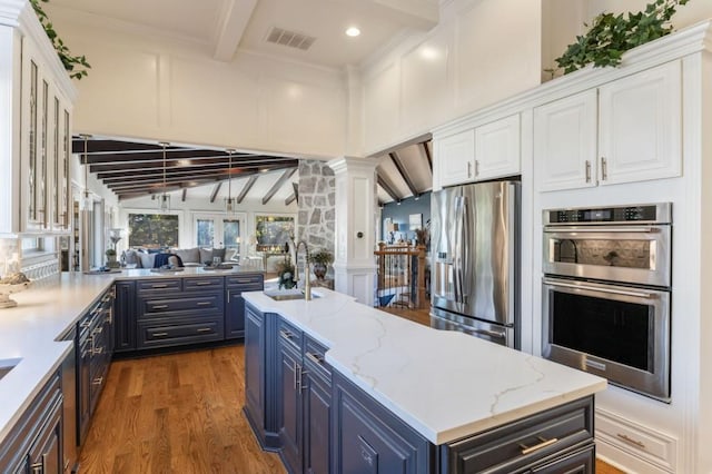 kitchen featuring decorative columns, white cabinetry, appliances with stainless steel finishes, and blue cabinetry