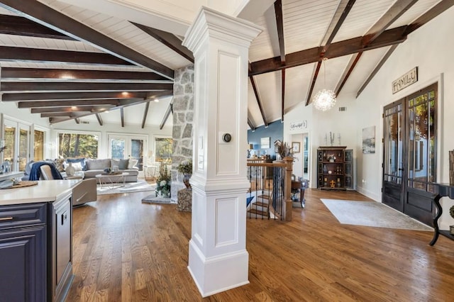 foyer entrance featuring french doors, vaulted ceiling with beams, dark hardwood / wood-style flooring, a notable chandelier, and decorative columns