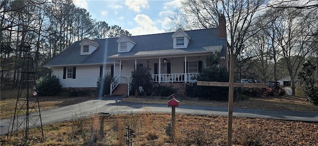 cape cod house with a porch and a chimney