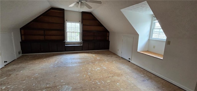 bonus room featuring vaulted ceiling, ceiling fan, a textured ceiling, and a healthy amount of sunlight