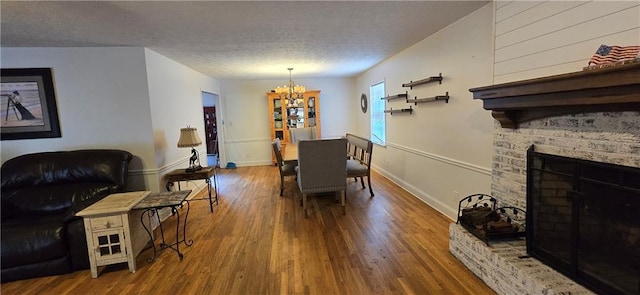 dining area featuring a notable chandelier, a textured ceiling, baseboards, and wood finished floors