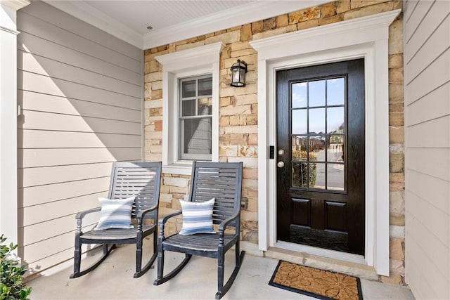 entrance to property featuring stone siding and a porch