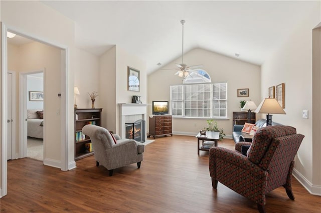 living room featuring ceiling fan, dark wood-type flooring, a tile fireplace, and vaulted ceiling