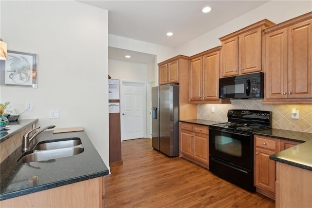 kitchen featuring dark stone countertops, sink, black appliances, and light hardwood / wood-style flooring