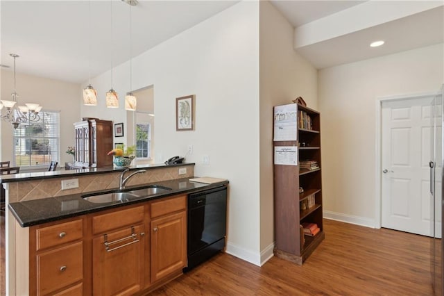 kitchen featuring sink, black dishwasher, kitchen peninsula, dark stone countertops, and plenty of natural light