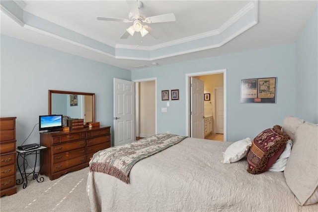 bedroom featuring ensuite bath, ornamental molding, light colored carpet, a raised ceiling, and ceiling fan