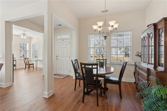 dining space with hardwood / wood-style floors and ceiling fan with notable chandelier