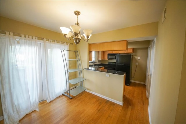 kitchen with black appliances, sink, light wood-type flooring, decorative light fixtures, and kitchen peninsula