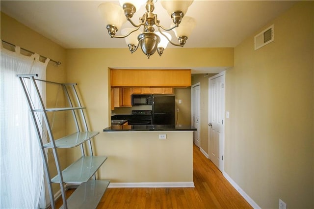 kitchen featuring black appliances, light wood-type flooring, kitchen peninsula, and a chandelier