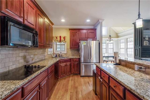 kitchen featuring pendant lighting, light hardwood / wood-style floors, ornamental molding, and black appliances