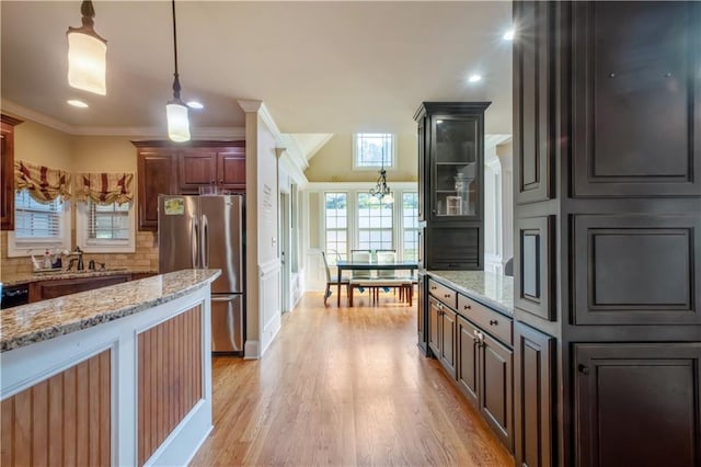 kitchen featuring stainless steel fridge, sink, light hardwood / wood-style flooring, light stone countertops, and crown molding