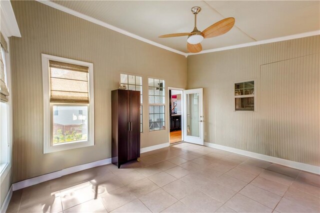 spare room with a healthy amount of sunlight, light tile patterned floors, ornamental molding, and ceiling fan