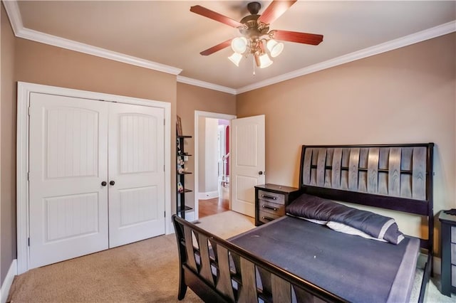 carpeted bedroom featuring ornamental molding, a closet, and ceiling fan