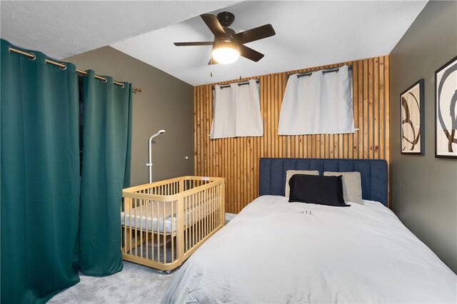 carpeted bedroom with ceiling fan and wooden walls