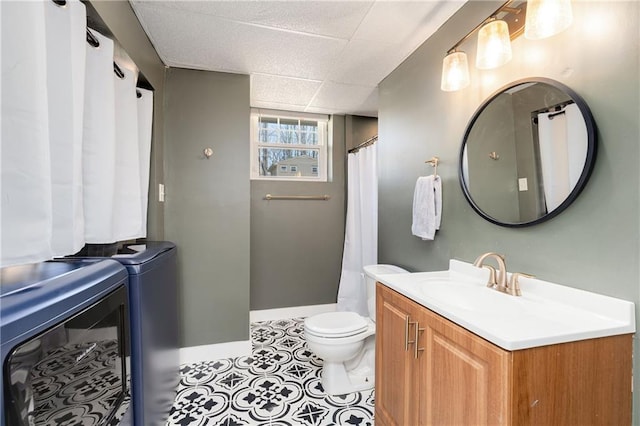 bathroom featuring baseboards, toilet, tile patterned flooring, vanity, and washing machine and dryer