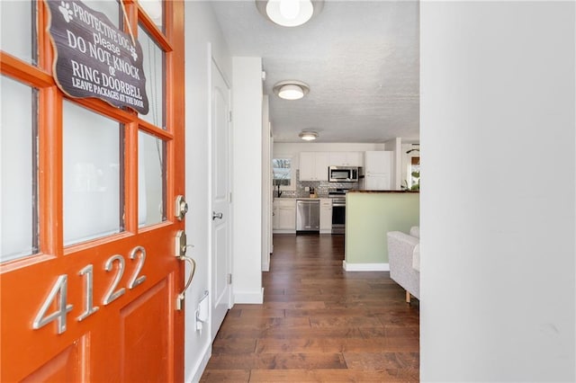 foyer featuring a textured ceiling, dark wood-style flooring, and baseboards