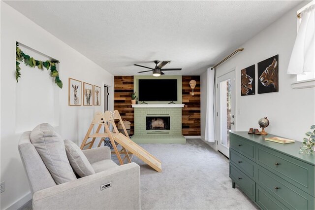 living area with light carpet, wooden walls, ceiling fan, a textured ceiling, and a fireplace