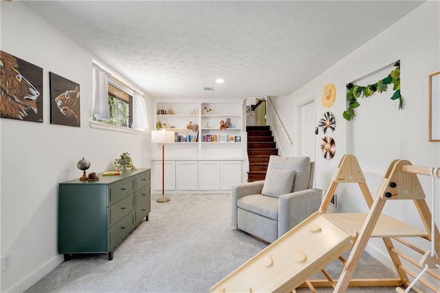 living area featuring light carpet, stairway, a textured ceiling, and baseboards