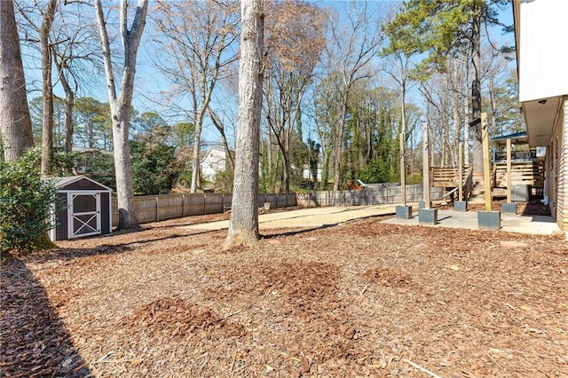 view of yard with stairs, a shed, an outdoor structure, and a fenced backyard