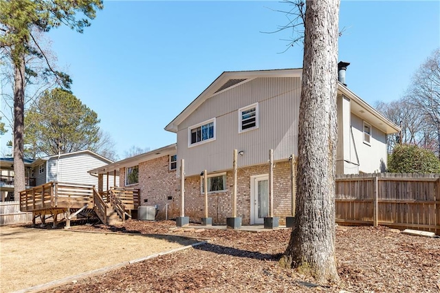 back of property featuring brick siding, fence, a wooden deck, and central air condition unit