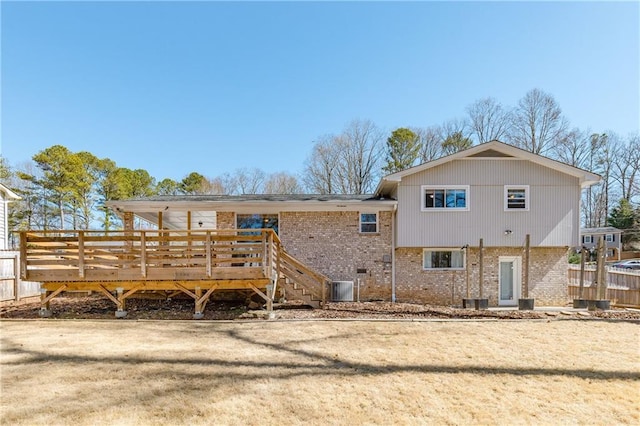 back of property featuring fence, a deck, and brick siding