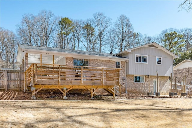 back of property with fence, a deck, and brick siding