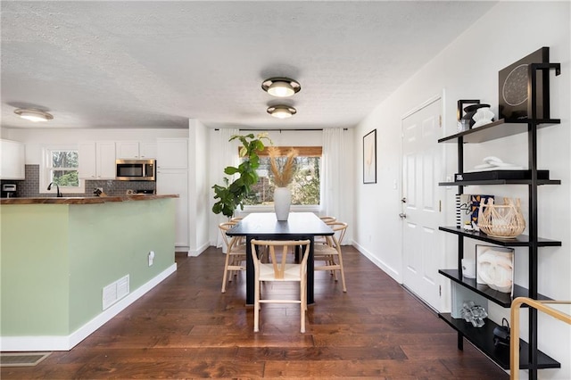 dining space with dark wood-style floors, a textured ceiling, visible vents, and baseboards