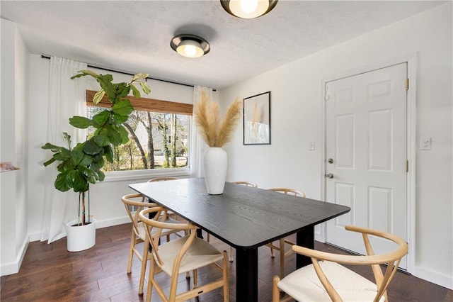 dining room featuring a textured ceiling, baseboards, and wood finished floors