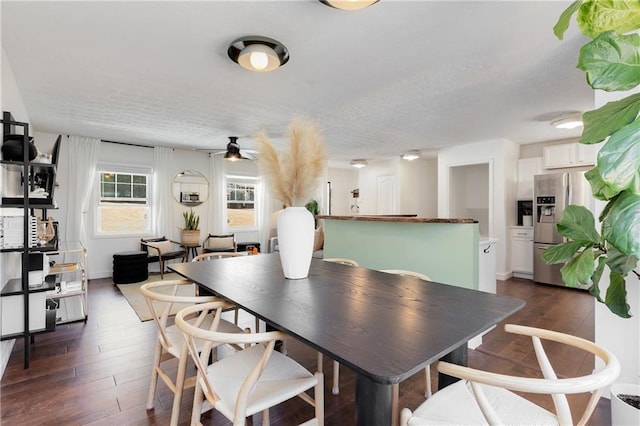 dining area featuring dark wood-type flooring, a textured ceiling, baseboards, and a ceiling fan