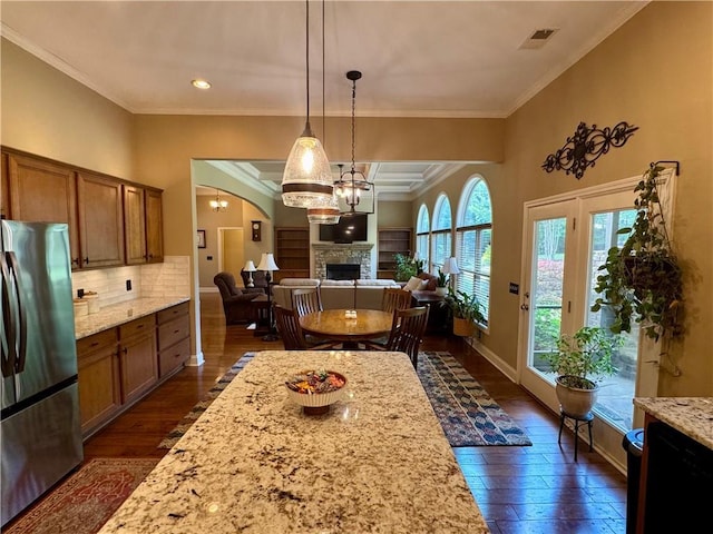 dining area featuring visible vents, a fireplace, baseboards, dark wood-style floors, and ornamental molding