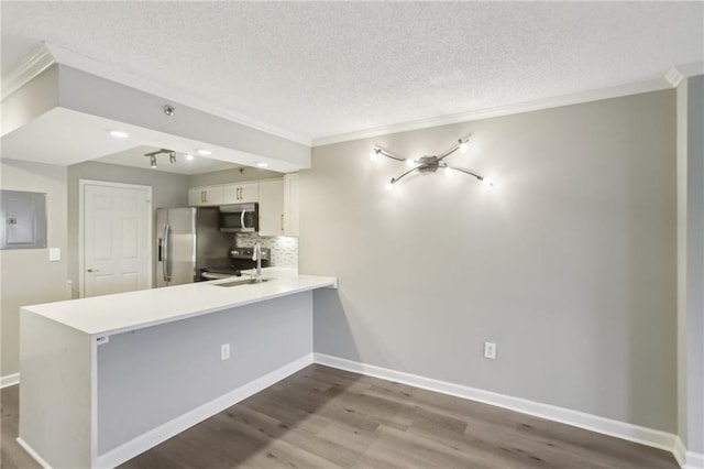 kitchen with appliances with stainless steel finishes, tasteful backsplash, ornamental molding, white cabinets, and kitchen peninsula