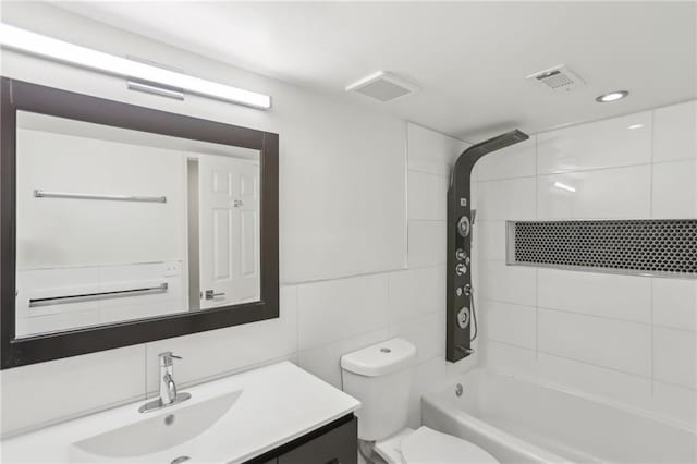 full bathroom featuring tile walls, backsplash, tiled shower / bath combo, vanity, and toilet