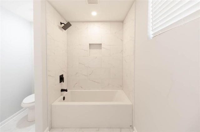 bathroom with tiled shower / bath combo and toilet