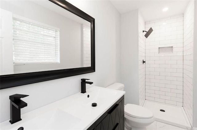 bathroom with vanity, a tile shower, and toilet