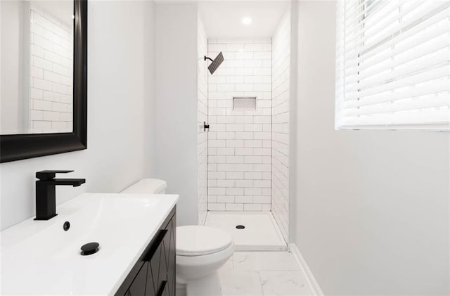 bathroom featuring toilet, a healthy amount of sunlight, vanity, and tiled shower