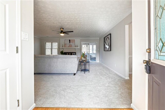 unfurnished living room featuring a fireplace, ceiling fan, light colored carpet, and a textured ceiling