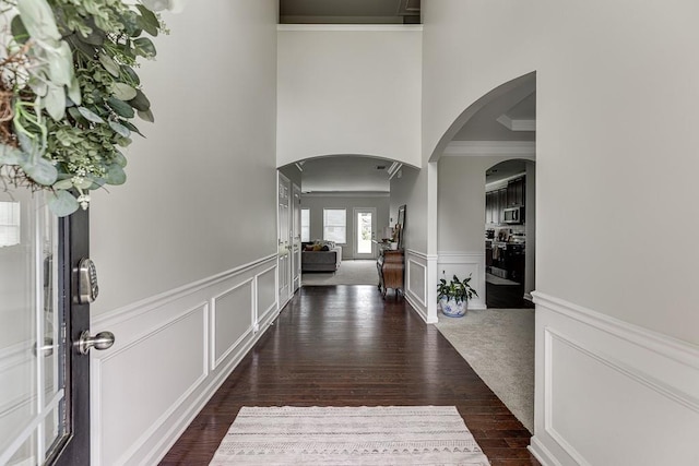 862 Blind Brook Cir, Hoschton, GA 30548 - foyer with a decorative wall, crown molding, dark wood-style flooring, wainscoting, and arched walkways