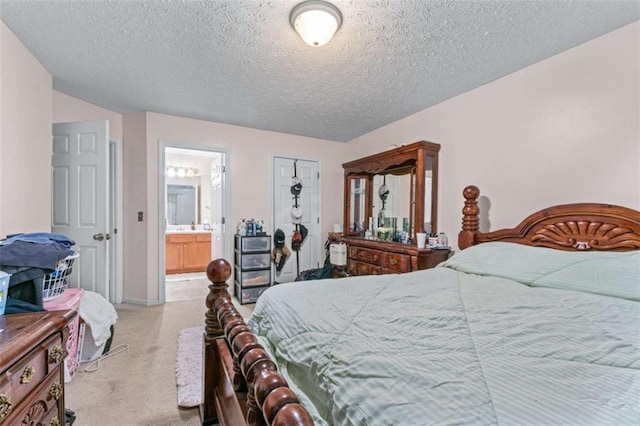 bedroom featuring ensuite bathroom, baseboards, carpet floors, and a textured ceiling