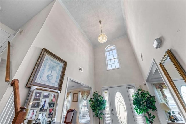 foyer entrance with visible vents, lofted ceiling, and ornamental molding