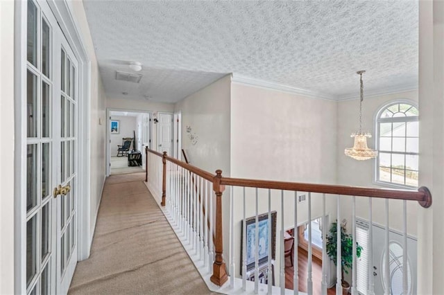 hall with crown molding, a chandelier, carpet floors, french doors, and a textured ceiling