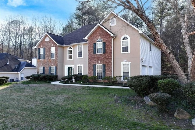 colonial-style house featuring stucco siding, brick siding, central AC unit, and a front lawn