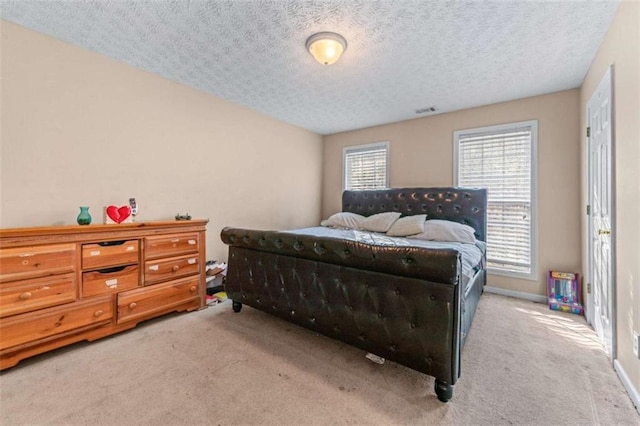 bedroom featuring visible vents, a textured ceiling, baseboards, and carpet floors