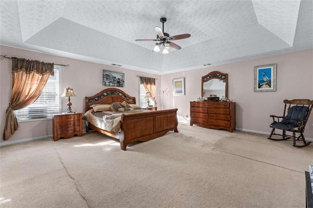 carpeted bedroom with baseboards, a raised ceiling, a textured ceiling, and a ceiling fan